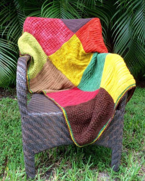 A colorful knitted blanket draped over an outdoor chair